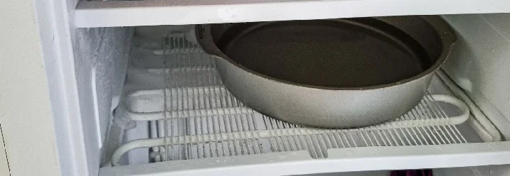 Hand legt Eisplatte in Gefrierschrank